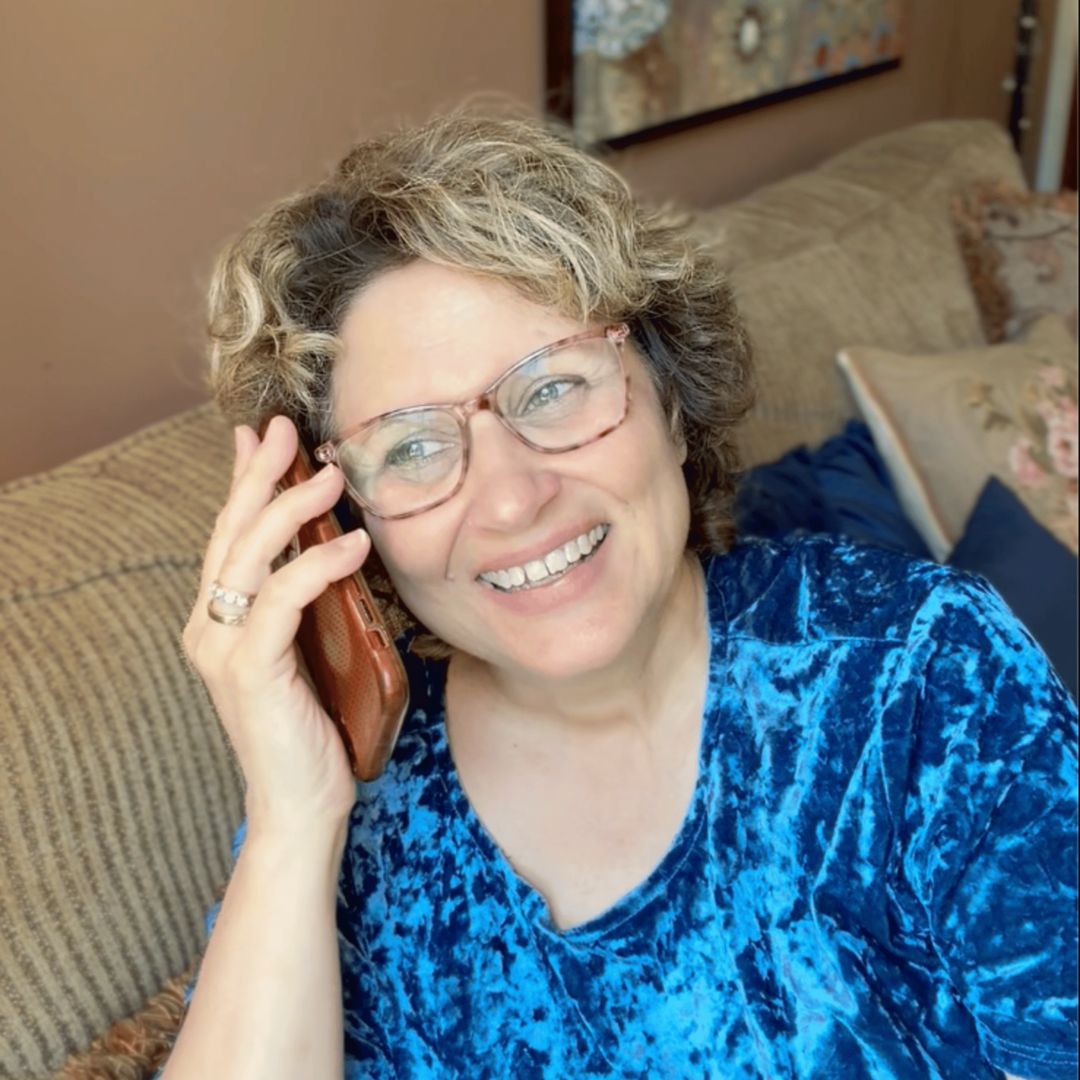 A woman smiling while sharing a story on a phone call