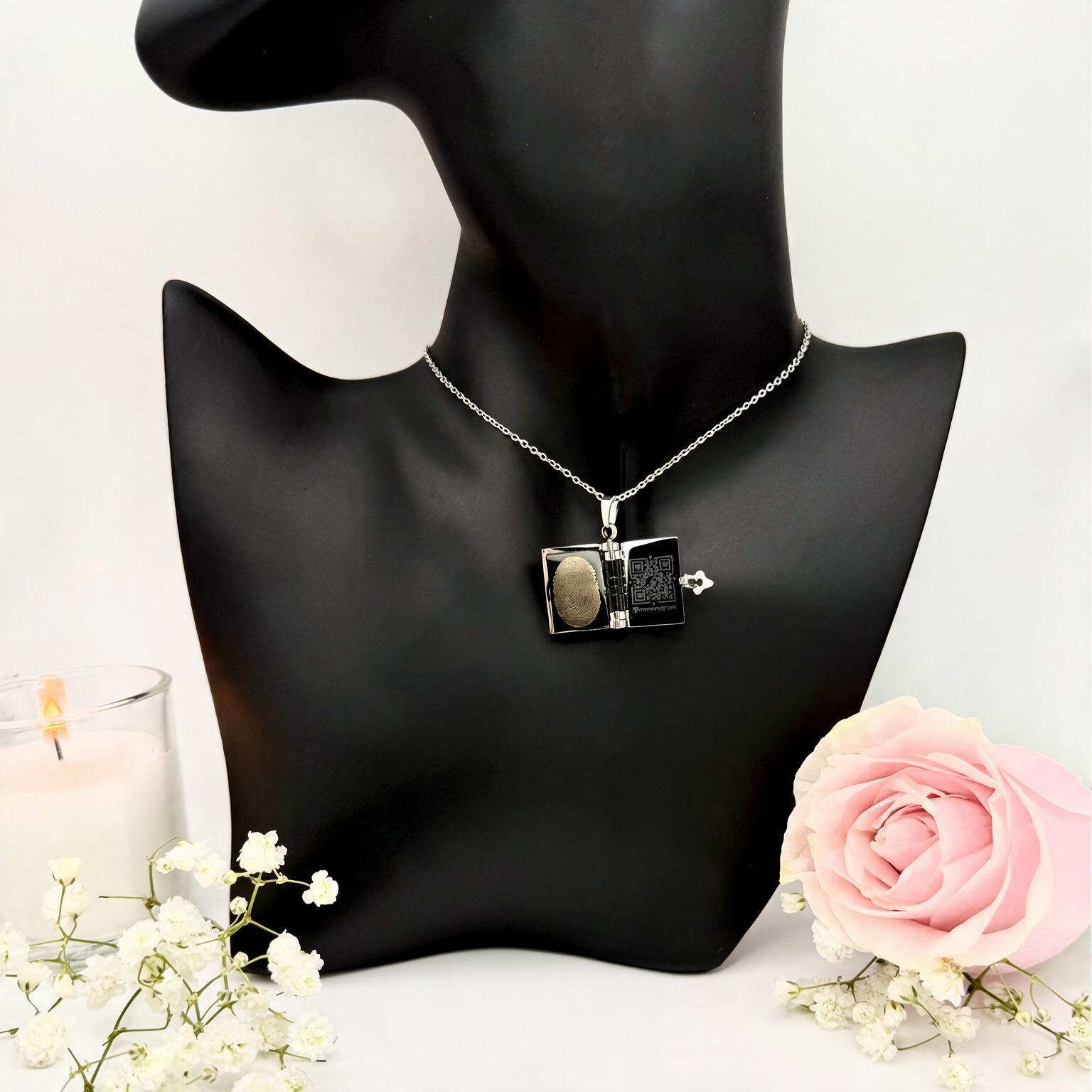 Open book necklace with engraved fingerprint and QR code linking to Virtual Memorial